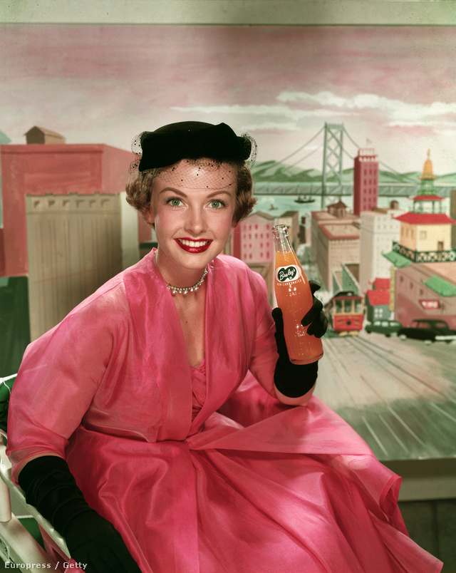  Trudy Wroe modell egy rózsaszín ruhában és fekete kalapban illetve kesztyűben reklámozott szénsavmentes narancslevet 1950-ben. 
