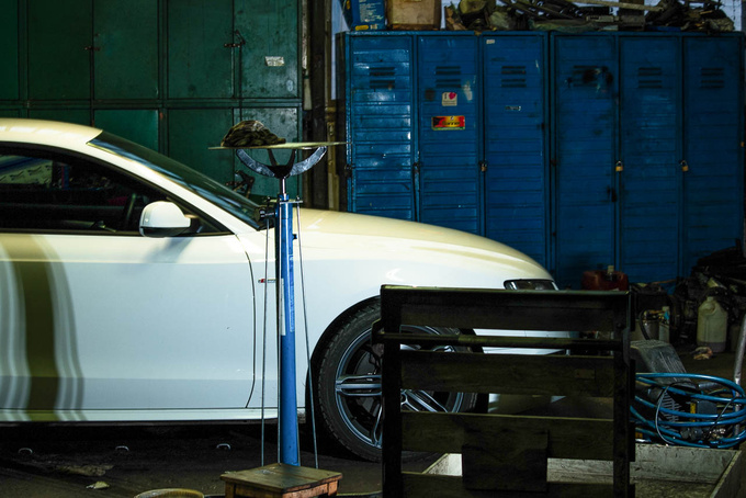 There is a sharp contrast between the pearl white Audi A5 and the workshop. They have worked on Bentleys here, too
