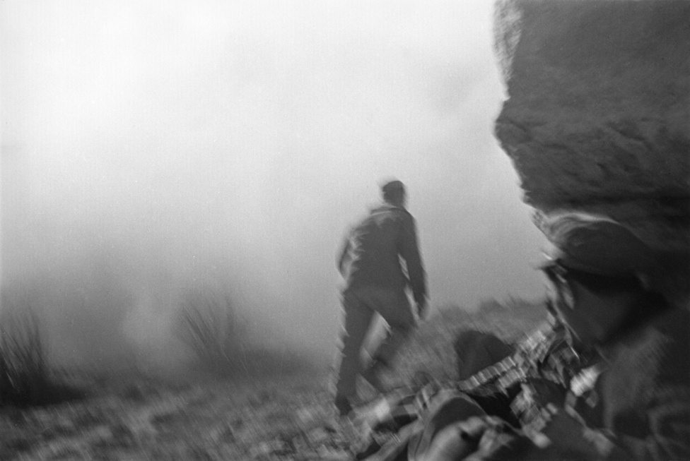 Köztársasági katona a Rio Segre-i csatában, 1938.&nbsp;A bemozdult fotó Capa későbbi partraszállós képeire rímel. A bőrönd képeiből kiderül az is, amire itt csak utal a sűrű füst: erős tűz alatt voltak, amikor ezek a fotók készültek.