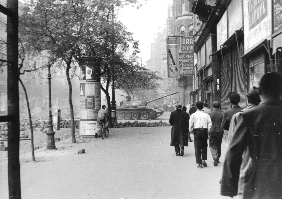 1956. "Járókelők" sétálnak az Erzsébet körúton látszólag olyan nyugalommal, mintha az ott előttük nem egy tank, csak egy kiforduló troli lenne. Csak a kerékpáros tűnik úgy, mintha fedezéknek használná a hirdetőoszlopot.