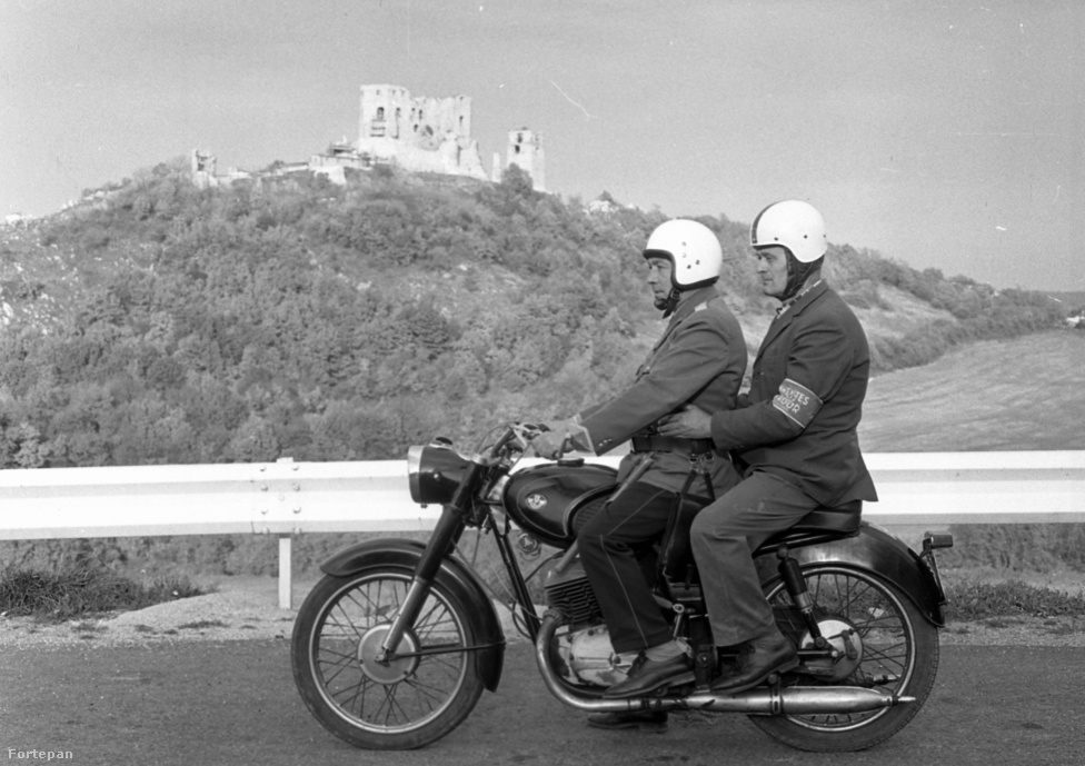 Az 1980-ban készült fotón motoros rendőr viszi az önkéntest rendőrt, mögöttük a Cseszneki vár.