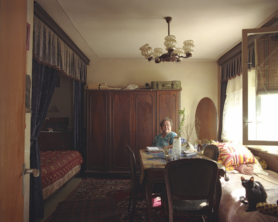 A fotós készítette alaprajz szerint a 10/1-es ház lakásai így néznek ki: ha az ember belép az ajtón, bal kéz felé esik a szoba, jobbra a fürdő és a konyha. A szoba alapja egy nagyjából négy és félszer négy és fél méteres négyzet, de az egyik sarkából lecsíp az előszoba. Az egész lakás összesen úgy 28 négyzetméter.
                        A nyugdíjas Suhariuc Ioana asszony baldachinos ágyára a magyarázat: a ház közel van a piachoz, és ő néha szállást ad olyanoknak, akik a piacra mennek árulni. A vendégek alszanak a baldachin alatt, ő meg az ablaknál lévő ágyon. 1967 óta itt lakik, 1982 óta egyedül, leszámítva a macskát, aki 1989-ben csatlakozott hozzá.