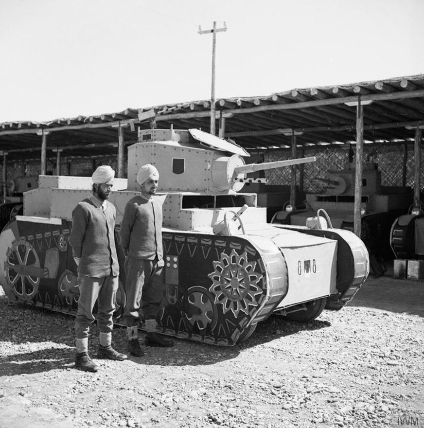 Két szikh harcos az indiai hadsereg álcázóezredéből egy autóból kialakított Stuart tank mellett 1942. március 25-én. Az álcázás, a trükközés minden hadszíntéren és minden hadseregnél jelen volt, a hadseregek békeidőben kellékesként, filmesként vagy épp festő- vagy szobrászművészként dolgozó civileket hívtak be, hogy segítsenek a műveletekben.