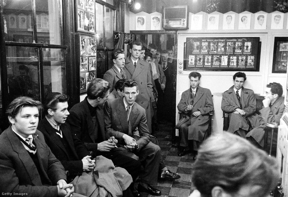 Fiatalok várakoznak a fodrásznál Hounslow-ban (1953). Bár a teddy boy kifejezés először 1953 októberében jelent meg a Daily Mirrorban, a londoni újságok már két évvel azelőtt is cikkeztek bandákba tömörült, elegánsan öltöző fiatalokról, akik nemcsak fiatalabbak, de erőszakosabbak is voltak a spiveknél. Eleinte „cosh boy”-ként (kb. ólmosbotos fiúk) emlegették őket, de később az Edwardian lett az állandó jelző, és ebből lett a teddy boy. 