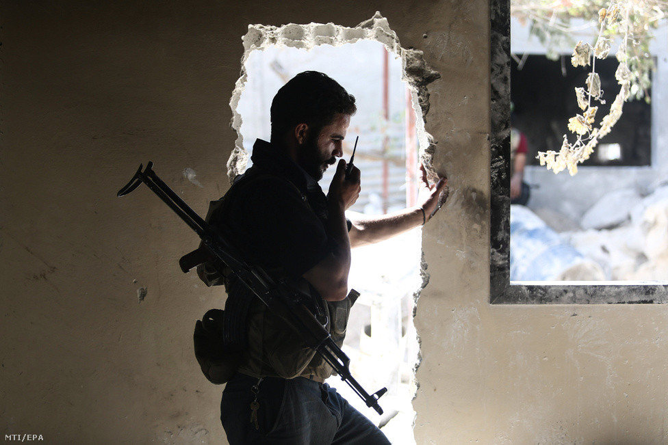 Az ellenzéki Iszlám Hadsereg nevű szervezet egyik katonája rádiózik társaival egy lerombolt épület ajtajában.