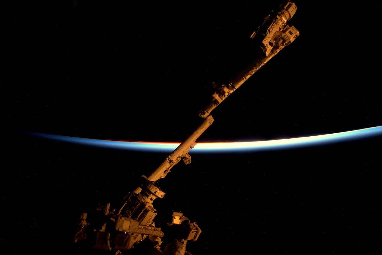 Az űrállomás robotkarja, a Canadarm, a háttérben egy naplemente utolsó pillanata.