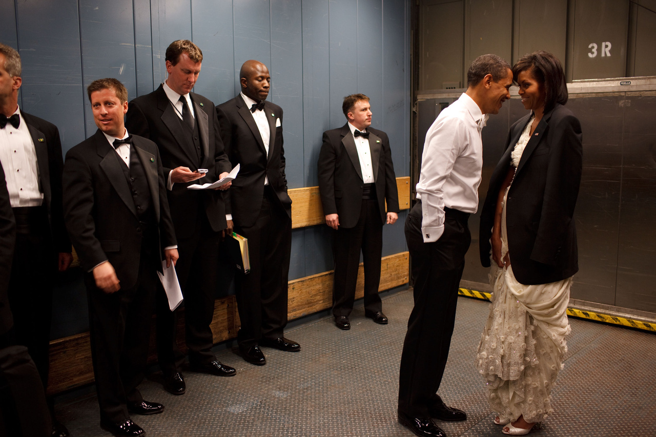 Egy meghitt pillanat a liftre váró Obama és a first lady között, testőrök és inasok sorfalával. Ez az ikonikus fotó még Obama első győzelme után készült.