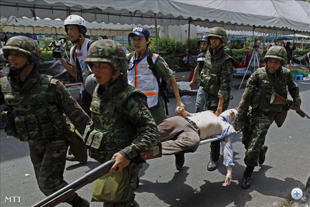 Sebesült külföldi újságírót visznek mentőautóhoz Bangkokban 2010. május 19-én, miután a hadsereg megindította a támadást a thaiföldi főváros központjának egy részét megszállva tartó vörösinges lázadók ellen