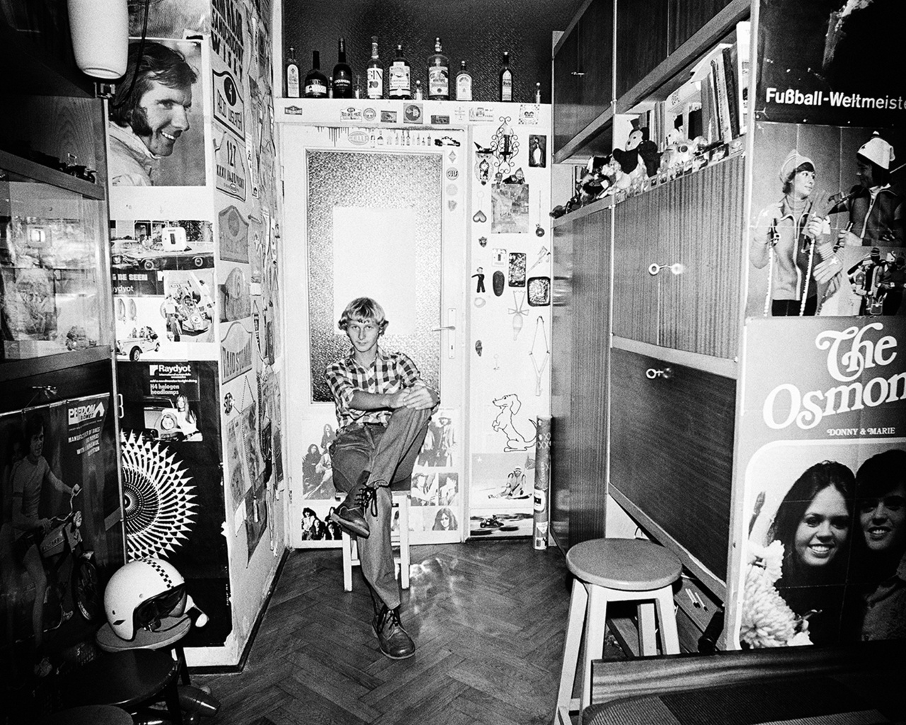 Jackie Stewart, The Osmonds, márkás nyugati italok és saját bukó a szekrénysor előtt. Rydet időnként belenyúlt a környezetbe: a felvétel előtt némileg átrendezte a szobában lévő tárgyakat, kisebb kompozíciót hozott létre az asztalon lévő dolgokból, egy-egy fotót a falon áthelyezett.