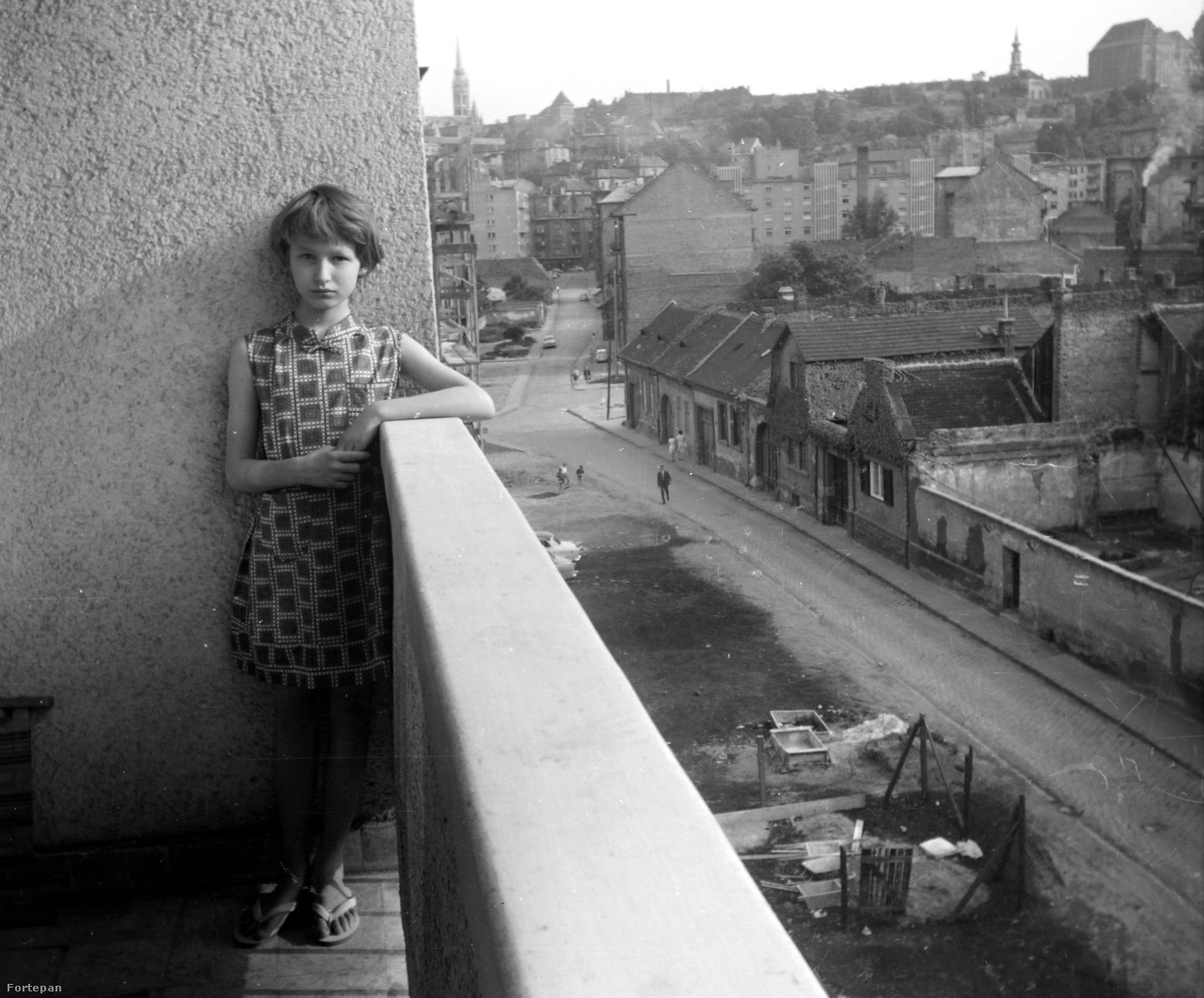 Két világ határán 1966-ban: egy modern épület lodzsáján támaszkodó lányka a Horváth utcában, a másik oldalon még a régi Buda emlékei földszintes házakkal. Ma már irodaházak vannak a helyükön.