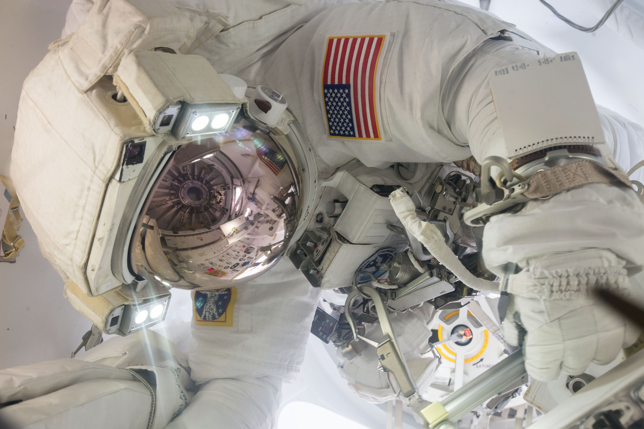 Jack Fischer NASA űrhajós űrsétára készül, sisakjának üvegén a légzsilip ajtaja tükröződik