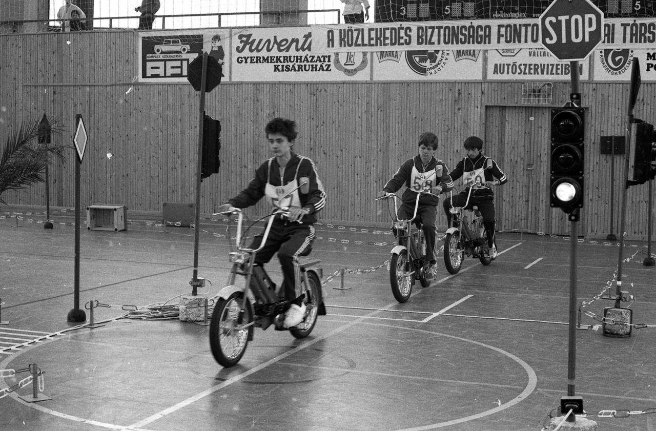 Az iskolásoknak KRESZ-vetélkedőket, ifjúsági közlekedésbiztonsági kupákat rendeztek. Ezen a képen a segéd-motorkerékpárosok szabályossági versenyének döntőjén Jawa Babettá-sok szlamoznak az egri körcsarnokban. De a Babettákig hosszú út vezetett az ötvenes évektől.