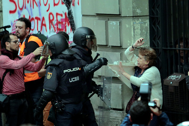 Egy idős nőt húznak ki a tömegből spanyol rohamrendőrök Barcelonában.