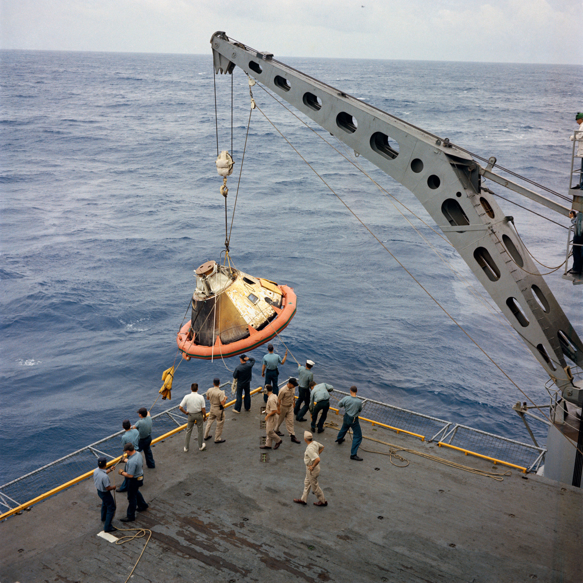 Az amerikai  haditengerészet USS Bennington repülőgéphordozójának fedélzetére emelik a Csendes-óceánba, Honolulutól 1730 kilométerre északnyugatra vízbe csapódó űrhajót. A CSM 017-et a dereka körül látható narancssárga “úszógumi“ tartotta a víz felszínén.