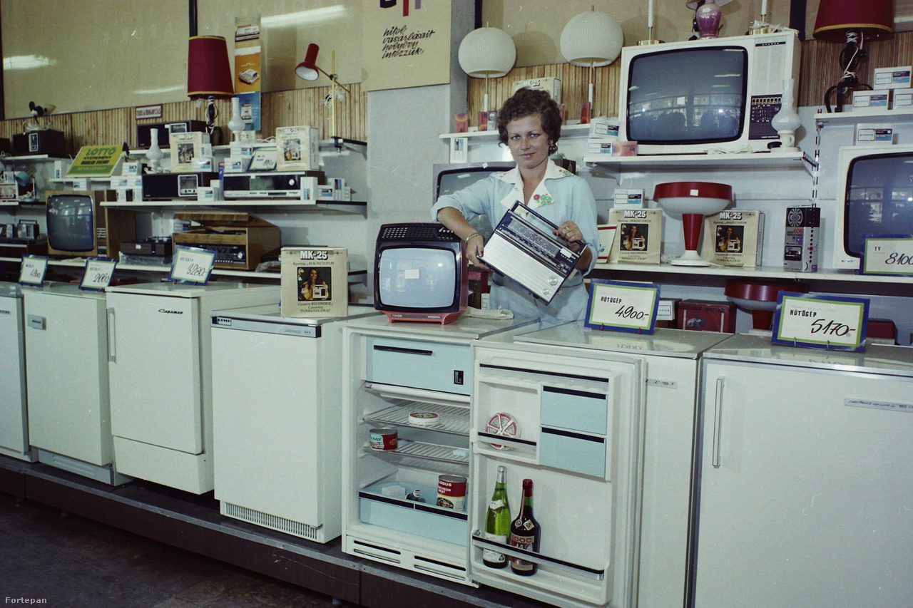 1974: a gödöllői Szövetkezeti Áruház műszaki osztályának kínálata. A Szabadság téri háztartási boltban a hűtőszekrényeken, fagyasztógépeken kívül olyan alapvető szocialista műszaki cikkeket lehetett kapni, mint például a VEF táskarádió, BRG MK-25 kazettás magnó, Videoton TC 1607 "Tünde" színes televízió. A hűtőben elhelyezett dekorációs termékek: Csárdás ömlesztett cikkelyes sajt, Globus löncshús, Pepsi-Cola, konzerv halászlé, fehér és vörös bor (Medoc, Kiváló Áruk Fóruma matricával).