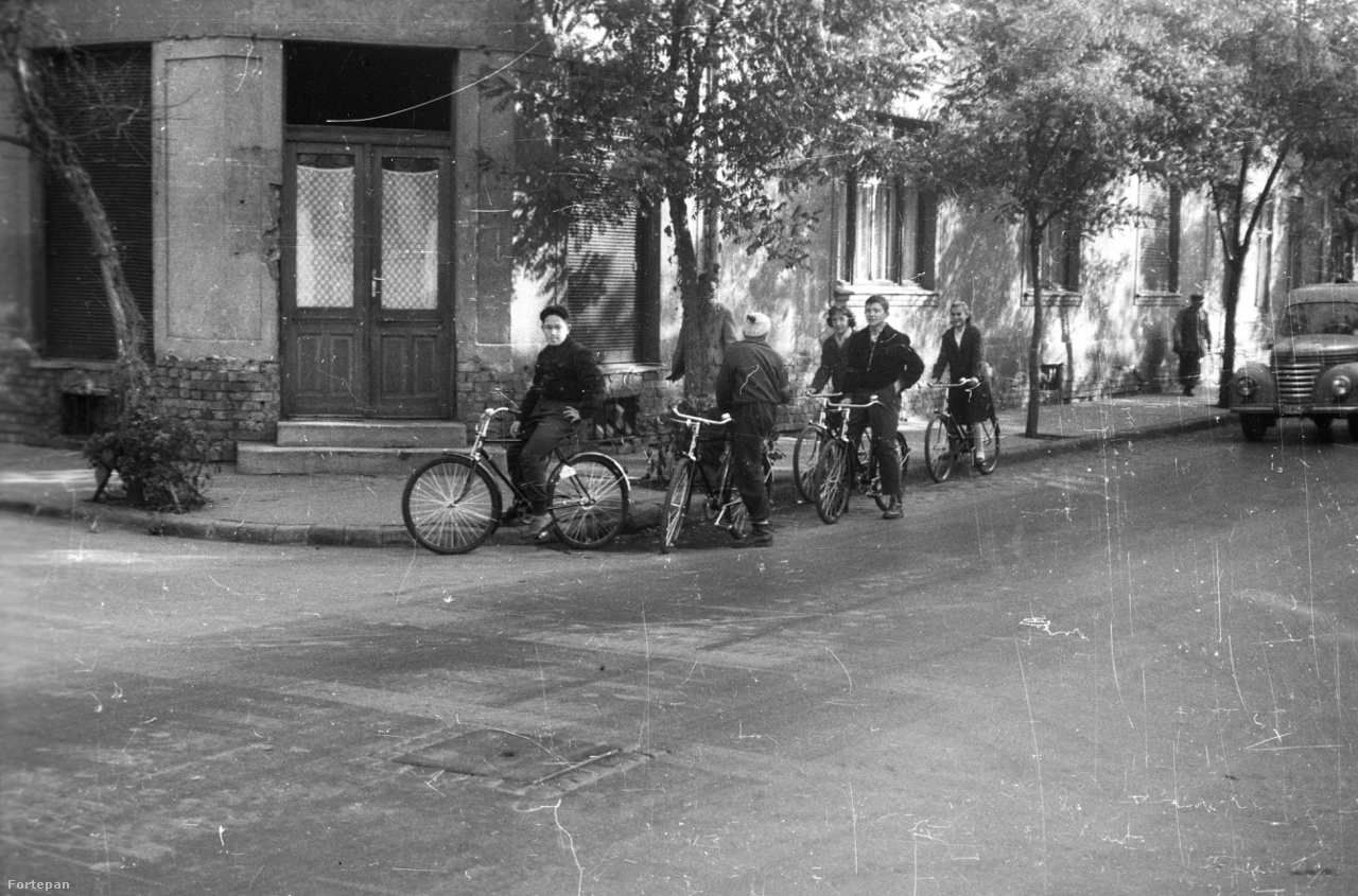 Két kép is készült ezen az ismeretlen helyszínen. A szerző az Esti
                        Hírlap fotóriportere, Sándor György. Vagyis itt is biztosra vehetjük,
                        hogy Budapesten készült a fotó, ránézésre valamelyik külső kerületben.
                        A biciklik gyanúsan újak. 