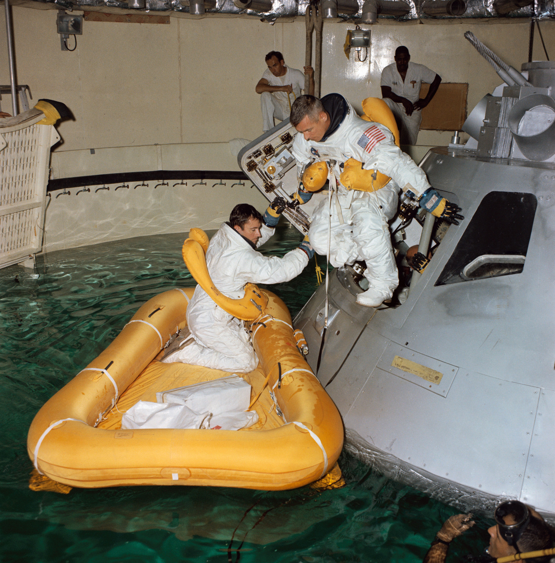 1968. augusztus 1. John W. Young (balra) és Eugene A. Cernan a vízre érkezés utáni kiszállást gyakorolják, harmadik társuk, Thomas P. Stafford még az Apollo űrhajó életnagyságú modelljének belsejében várakozik.