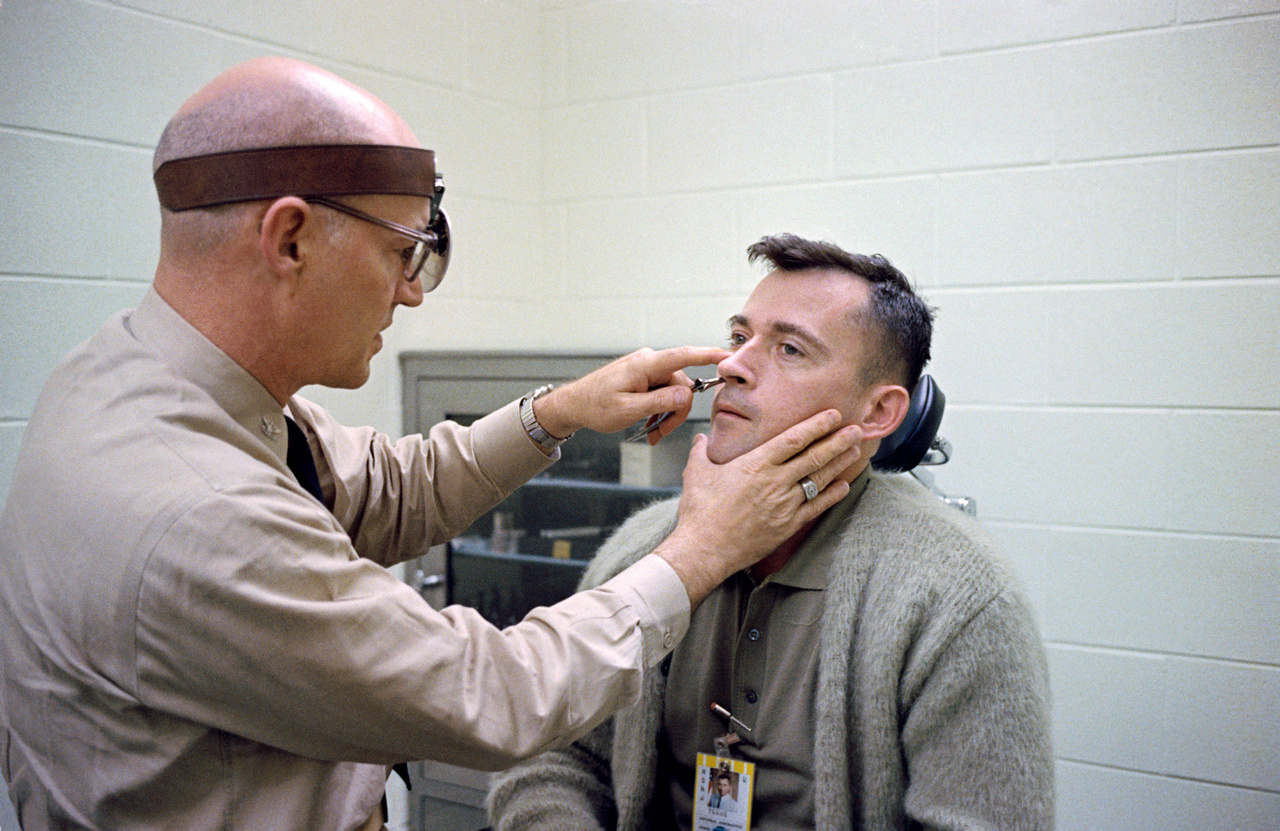1965. március 21. Young űrhajós fülét, orrát és torkát vizsgálja dr. Ballenberger a Gemini-3 startja előtti napokban..
                        