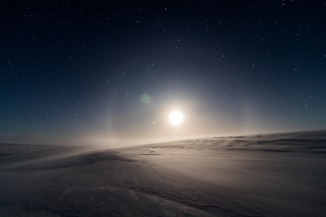Varázslatos antarktiszi éjszaka, csillagokkal, holdhalóval, sivatagi dűnékhez hasonlatos, szikrázó hótakaróval.