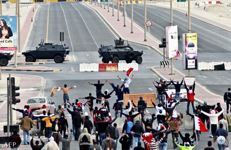 Kormányellenes tüntetők széttárják karjukat a katonai járművek láttan