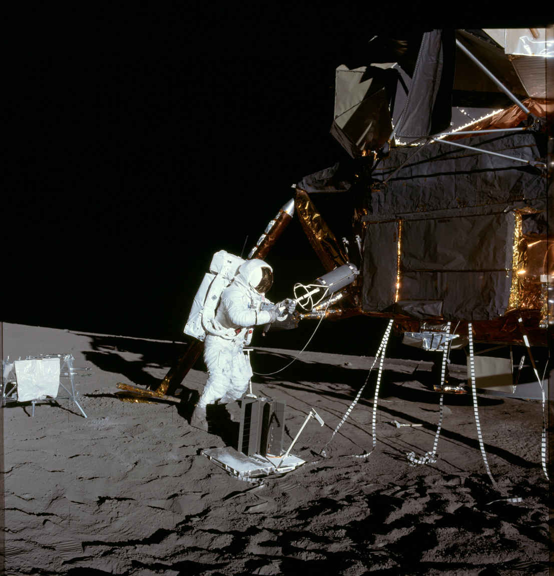 1969. november 19. Bean az első holsétán, épp leszereli a holdkompról a radioizotópos termoelektromos generátor (Radioisotope Thermoelectric Generator, RTG) üzemanyagtartályát. Az RTG a Hold felszínére telepített műszereket, kísérleti felszerelést (Apollo Lunar Surface Experiments Package, ALSEP) látja el energiával.