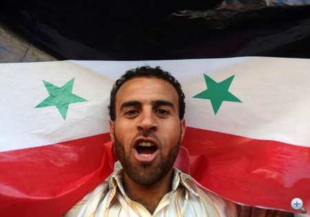 A szíriai kormányt támogató tüntető szír zászlóval a nyakában tüntet a beiruti szír nagykövetség előtt