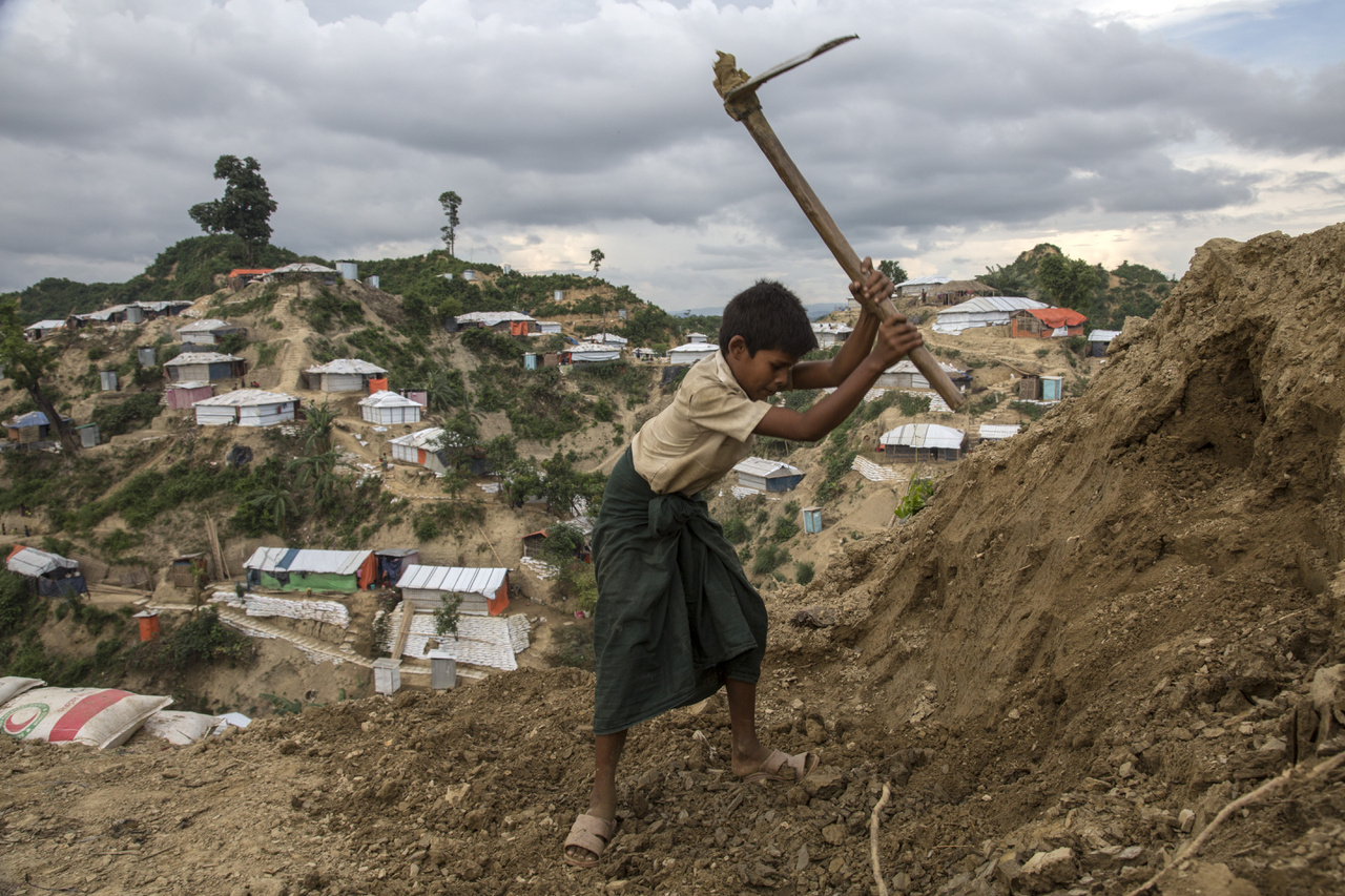 Rohingja fiú ássa a család új sátorhelyét a monszun érkezése előtt június 5-én. A saras domboldalakba épült sátortáborokban gyakoriak a kisebb földcsuszamlások, ilyenkor a sátorokat is könnyen elmoshatja az eső a domboldallal együtt. 