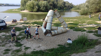 Olajoshordó-szobor és a felcímkézett uszadékfák a Duna-parton
