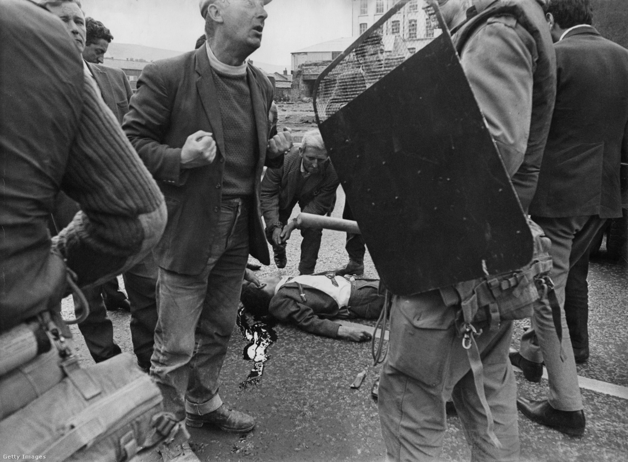 Súlyos sebesült fekszik az úton, miközben egy civil számon kér egy brit katonát az északír zavargások során 1969-ben.