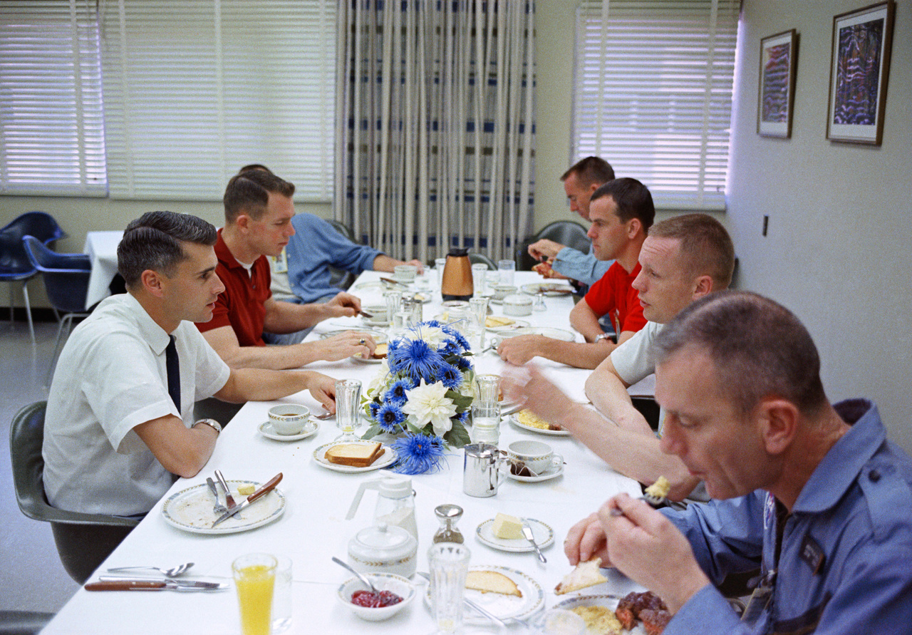 Fotó a NASA-archívumából: a Gemini-8 küldetés legénysége (Neil Armstrong, jobb oldalt alulról a 2., és David Scott, az asztal bal oldalán, alulról a 2., piros pólóingben) reggelizik steaket és tojást a start napján. Csatlakoztak hozzájuk fess űrhajóstársaik (Donald Slayton, Curtis Michel, Walter Cunningham, Alan Shepard és Roger B. Chaffee). 
