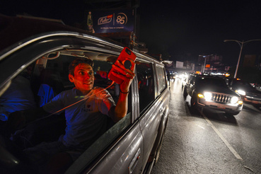 Emberek használják a mobiljukat a Francisco Fajardo főúton, ahol találnak térerőt az áramszünet idején Caracasban 2019. március 9-én