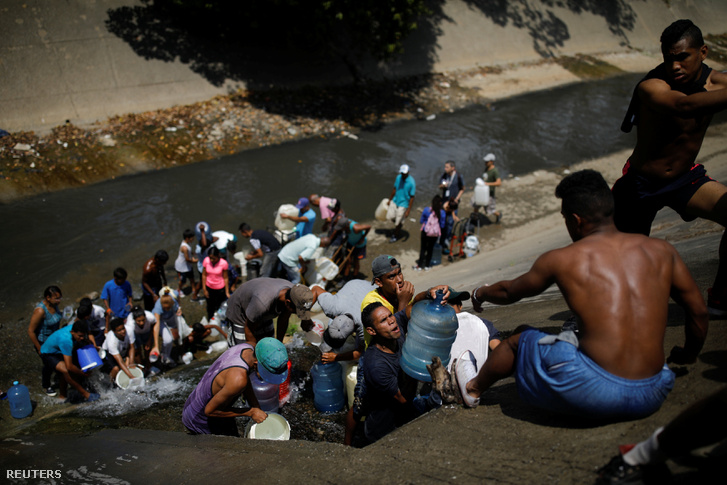 Emberek gyűjtik be a vizet a szennyvízcsatornán keresztül, ami a Guaire folyóba ömlik Caracas-ban 2019. március 11-én