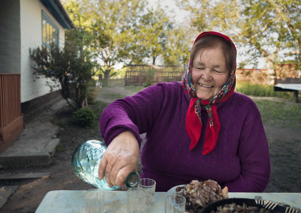 A Poltava területről származó Nina Alekszejivna derűsen itatja vendégeit az udvarán. "Két testvérével együtt szüleiket a háború alatt elveszítették. Emiatt a három árvát a falu nevelte fel. A három nővér gyönyörűen énekelt, és azzal hálálták meg a falusiak segítségét, hogy a közösség különböző ünnepein, vagy csak akár házról-házra járásként mindenkinek énekeltek. Nina mindkét testvére meghalt azóta, de jókedve és csodálatosan csengő hangja miatt az egész faluban köztiszteletnek örvend."