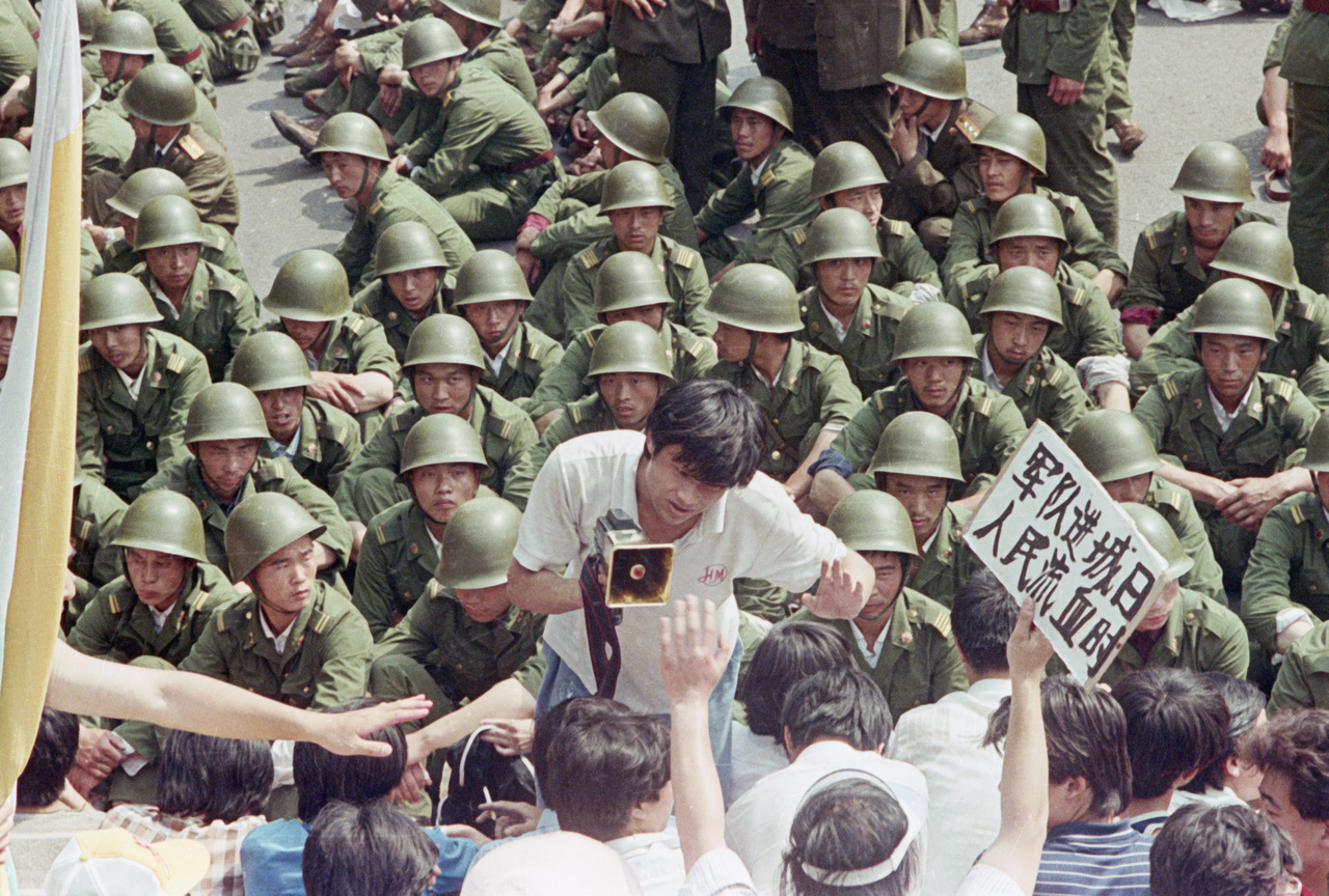 Katonák veszik körül a tüntető tömeget a Tienanmen téren. A demonstrálók élén egy fiatal, hangosbeszélővel a kezében. 