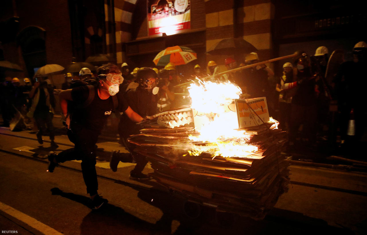 Meggyújtott dobozokat tolnak előre egy platformkocsin. A tüzek most a hagyományos Hungry Ghost Festival alatt is többeknél összekötődtek a tüntetésekkel. Ilyenkor füstölők és tüzek gyújtásával a szellemeknek és az ősöknek ajánlanak fel különböző tárgyakat, joss papírokat, amiket jelképesen elégetnek. A South China Morning Post szerint ezúttal több papíron is Carrie Lam hongkongi kormányzó arcképe volt. A pekingi vezetés bizalmát élvező Lam július 9-én halottnak nyilvánította a kiadatási tervezetet, de teljesen nem vonta vissza.