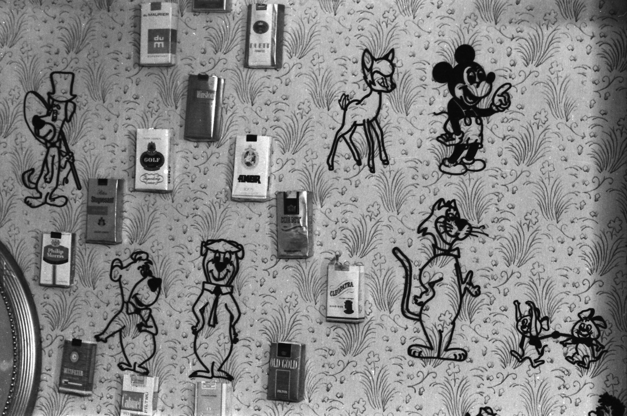 Fali dekoráció 1974-ből: cigarettásdobozok és rajzfilmfigurák a tapétán.