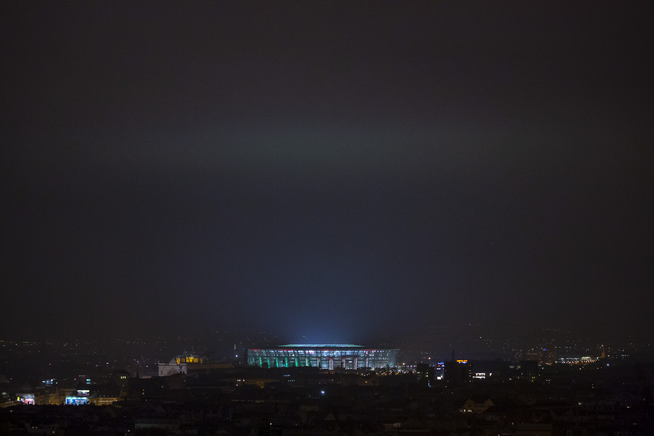 A díszkivilágítás színeit az alacsony felhőkre vetíti, így jelenhetnek meg a magyar zászló színei a stadion fölött az égen.