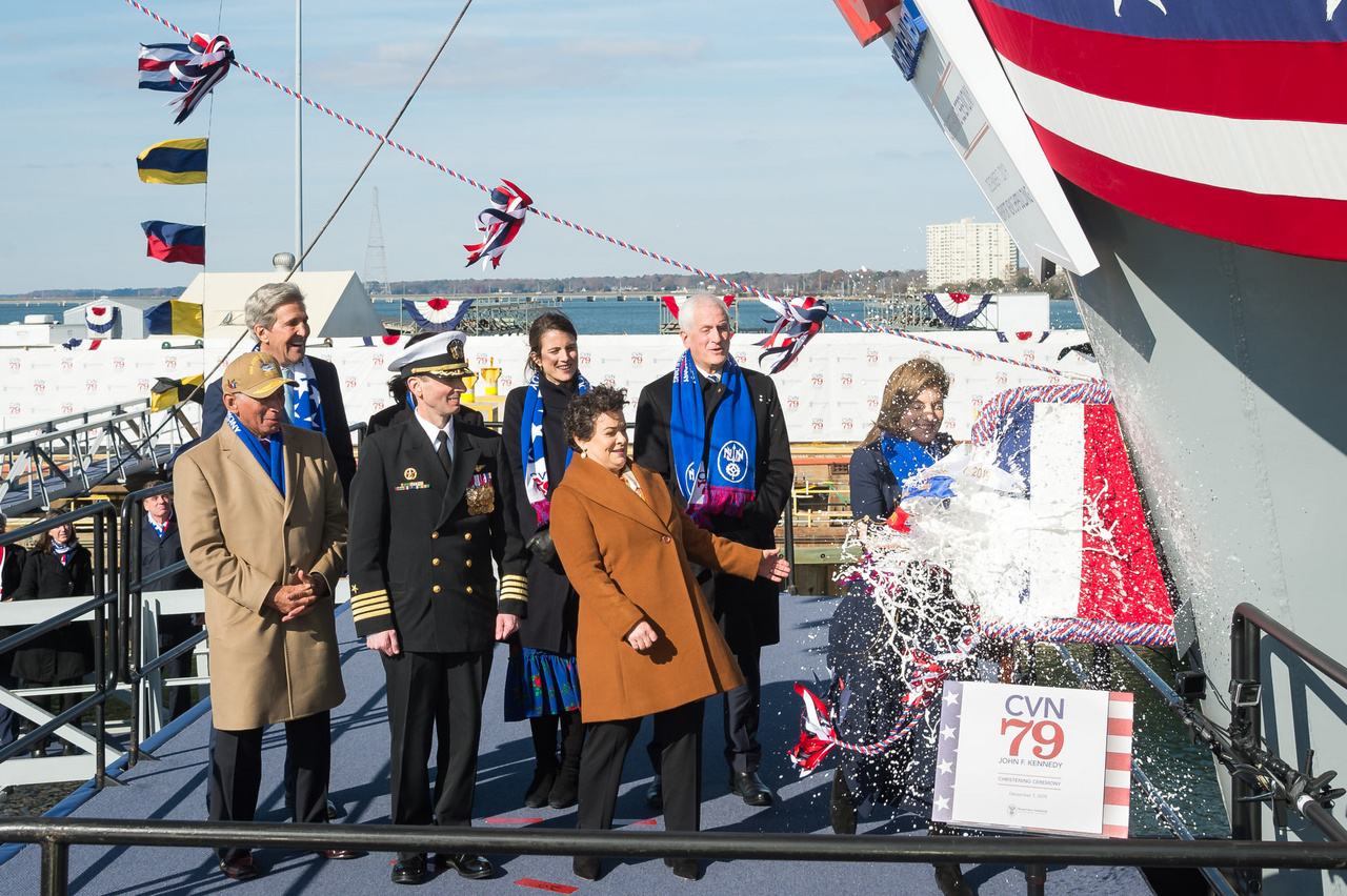 2019. december 7-én ünnepélyes keretek között keresztelte el a hajót Caroline Kennedy, a névadó, John F. Kennedy, néhai amerikai elnök lánya. A fotón illusztris társaság látható: bal szélen Charlie Bolden, a NASA előző igazgatója, mellette John Kerry, az USA korábbi külügyminisztere, Todd Marzano tengernagy, a hajó leendő parancsnoka (egyenruhában), illetve Jennifer Boykin, a Newport News hajógyár elnöke (barna kabátban), mögötte Caroline Kennedy lánya,Tatiana Schlossberg és veje, Edwin Schlossberg.