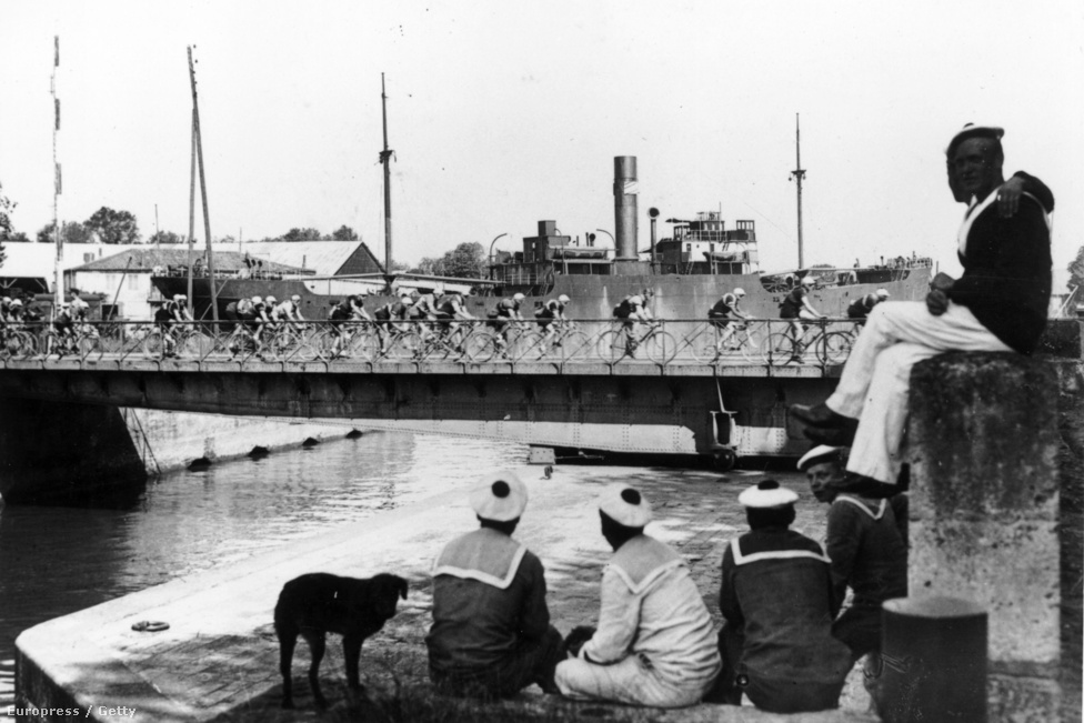 Matrózok nézik az 1925-ös verseny mezőnyét a a roqueforti kikötőben. A Tour ebben az évben szinte végig Franciaország határvonalain haladt, 5430 kilométeren.
                        