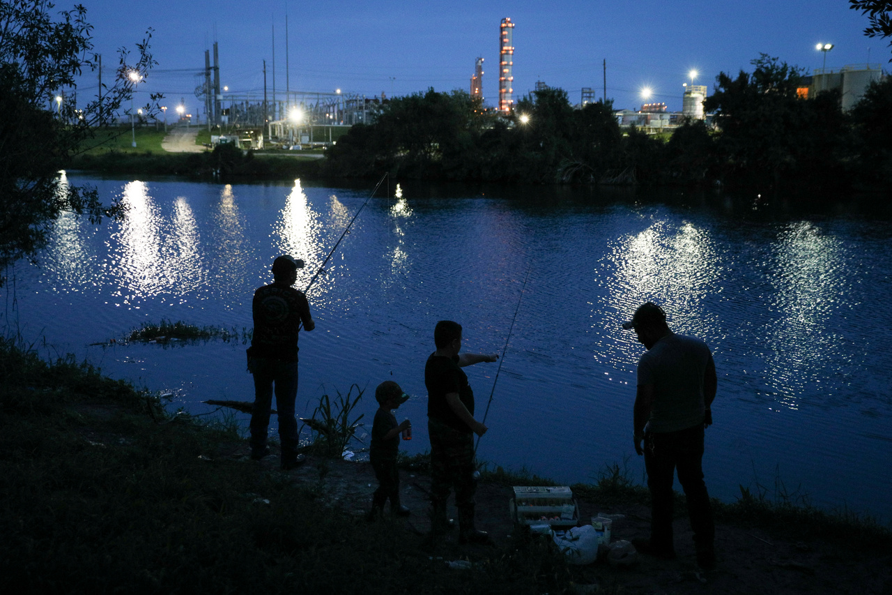 Horgászok a Houston-csatorna partján, szemben az olajfinomító fehér lángjai. 