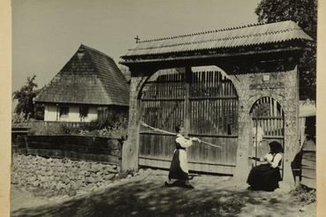 Fonó asszony és munkából hazatérő leány az utcán, a kapu előtt, Székelypálfalva