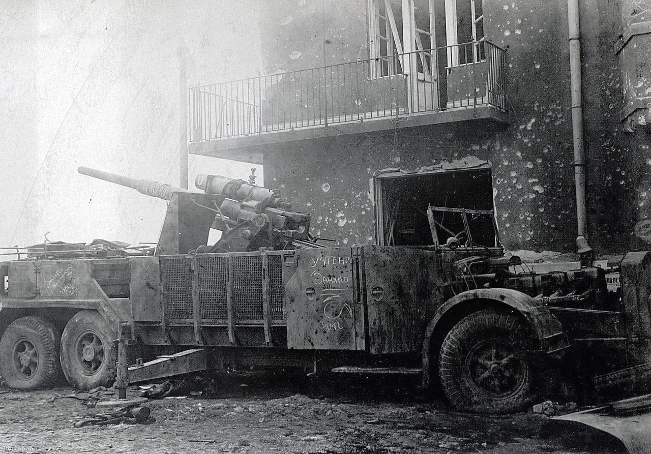 A Batthyány tér déli sarkán elhagyott német Vomag típusú önjáró légvédelmi löveg. A 88 milliméteres légvédelmi ágyút a Vogtländische Maschinenfabrik által gyártott buszalvázakra szerelve félelmetes hatékonyságú gyorstüzelő légvédelmi egységeket állítottak fel 1941 után. A gép oldalán látható orosz felirat arra utal, hogy a löveget a Vörös Hadsereg leltárba vette ("rögzítette") és lefoglalta. A mai utcaképet  ide kattintva nézheti meg.