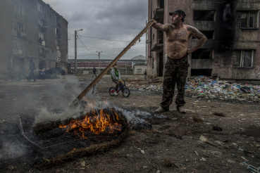 Egy roma férfi rugós matracot éget a fallal leválasztott Horea utcai gettóban, 2013