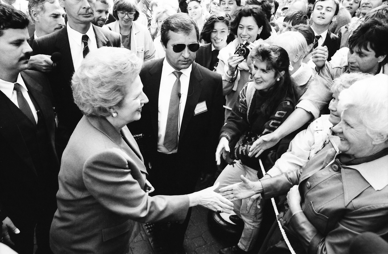 1990.szeptember 19, Budapest, Vörösmarty tér, Margaret Thatcher brit miniszterelnök.
                        
                        ___
                        
                        "Thatcher második és a dél-afrikainál is sokkal nagyobb teljesítménye volt a berlini fal leomlása. Ez sok kéz műve volt, ám a színdarab első felvonásában a nyugati főszerepeket ő és Reagan játszották (II. János Pál pápával együtt), majd Thatcher nagyon fontos mellékszerepet vitt a második felvonásban is. A fal leomlása két azonnali és nem sokkal később még egy harmadik reakciót váltott ki belőle. Először egyszerű, elsöprő örömet érzett afölött, hogy Közép- és Kelet-Európában az emberek visszanyerték a szabadságukat. Másodszor nyugtalan szorongás fogta el."  (John O'Sullivan: Margaret Thatcher 1989-ben.)