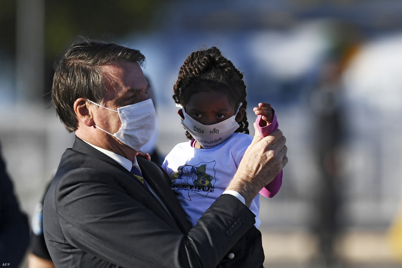 Május 12.A maszkos Bolsonaro egy kislányt tart a kezében egy zászlófelvonáson.&nbsp;