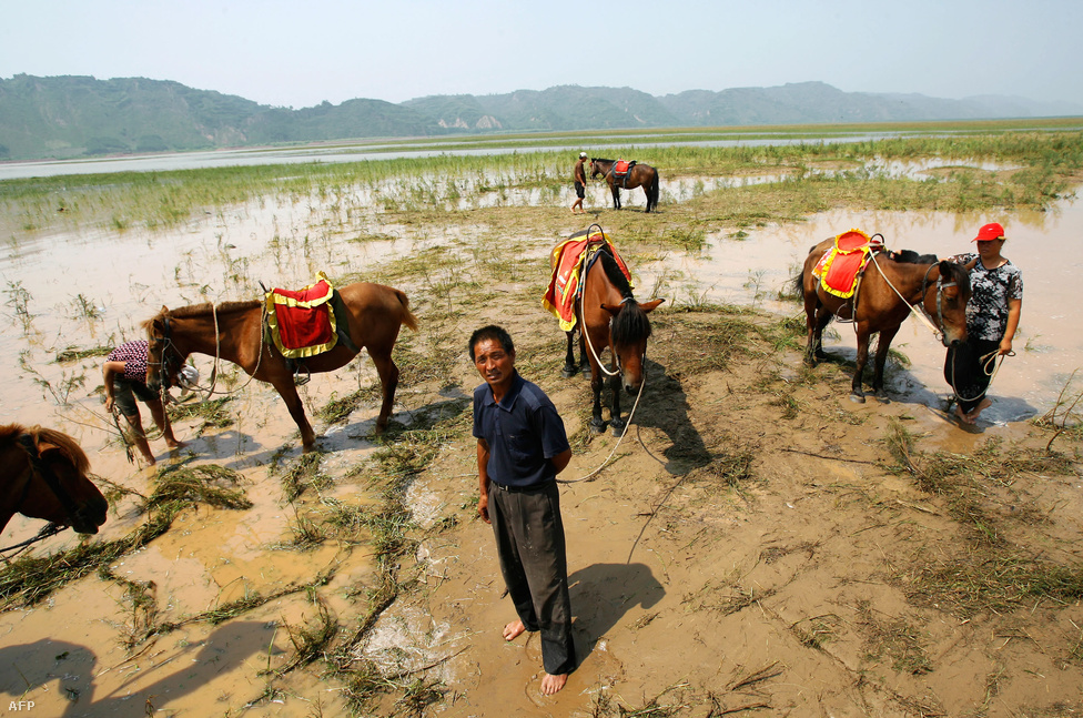 Kínai farmerek figyelik a turistákat a Sárga-folyó (Huang He) mentén az ország belsejében. Kína az elmúlt években nem csak ipari teljesítményben ugrott nagyot: 2006-óta Franciaország és Spanyolország mellett a legkedveltebb turisztikai úticélok egyike.