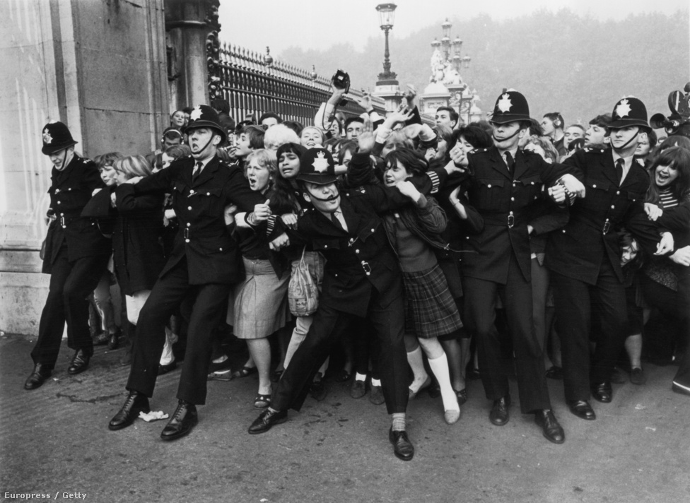 Rendőrök próbálják visszatartani a hisztérikus tömeget a Buckingham Palota kapujában a Beatles lovaggá ütésének napján.