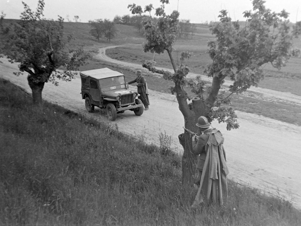 Igazoltatás a határon háttérbiztosítással (1949). A kommunista hatalomátvétel után készült fotó valószínűleg beállított volt: az autó katonai jármű, benne a sofőr uniformisban ül, és valódi helyzetben egy épeszű járőr sem egy ilyen fa mögött keresne magának fedezéket,  ahol ennyire tisztán kivehető lenne egy veszélyesnek ítélt autó számára.