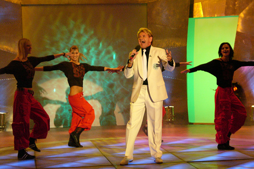 Komár egy 2004-es fellépésen, a szokásos, világos öltönyei egyikében. Az énekes a magyar Elvisként futott be karriert.