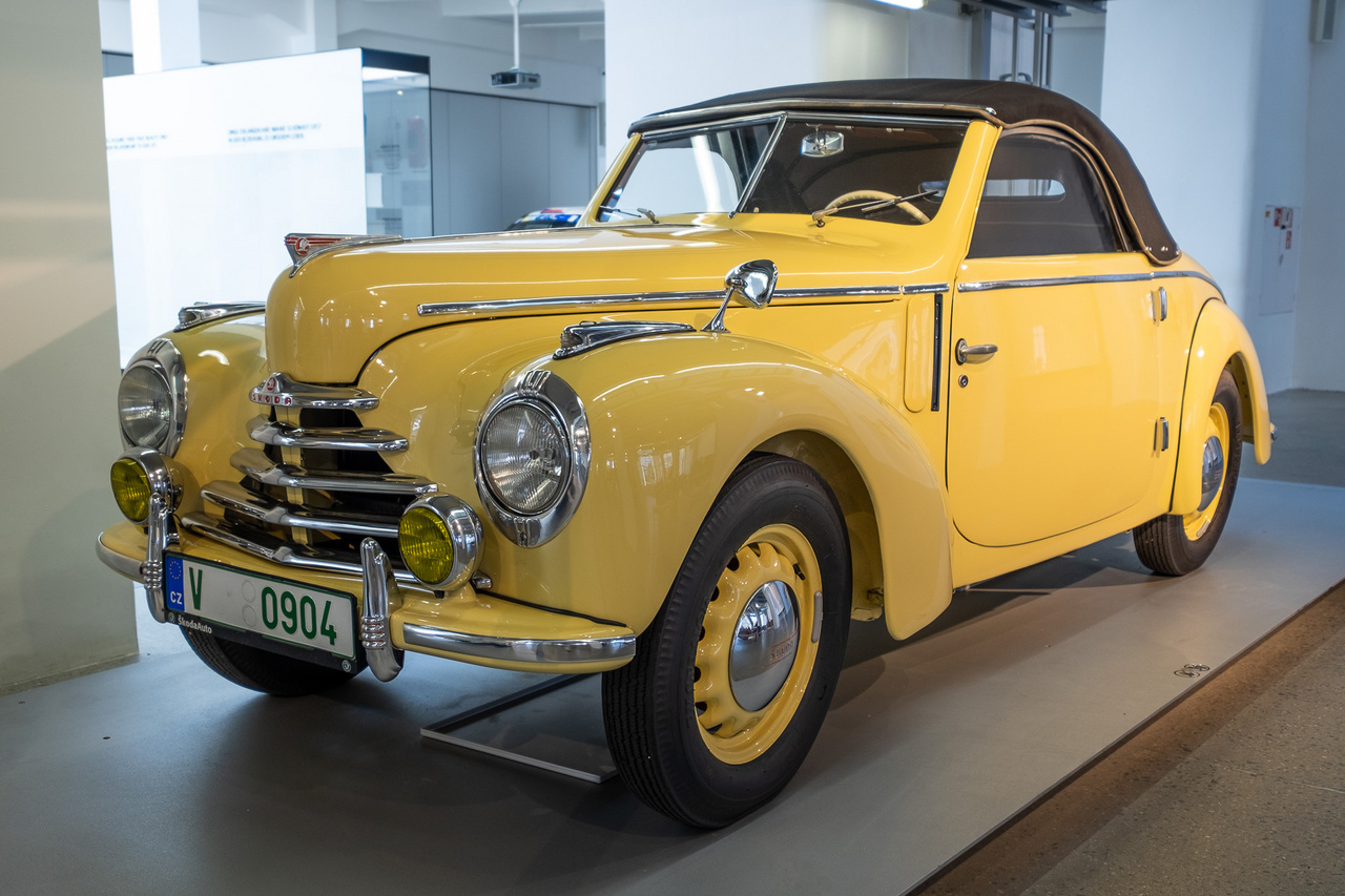 KÉP: Skoda 1100 a Skoda Museumban. Ahogy akkoriban oly sok mást, az autókereskedelmet is alapjaiban változtatta meg a Rákosi-korszak. 1951 májusától kizárólag az Autókereskedelmi Vállalaton, 1954-től az Autó és Alkatrészkereskedelmi Vállalaton keresztül lehetett új és használt gépjárművet értékesíteni. Évente néhány száz példányról volt szó, többek közt Tatraplanokról, Škoda 1101-esekről, de a felsőbb vezetésnek különlegesebb járművek is jutottak – a kapitalizmust folyton ekéző vezetők gyakran amerikai kocsikkal jártak. A képen is látható Škoda 1101-es népszerűbb neve Tudor volt, ami az angol two-door, vagyis kétajtós kifejezésből eredt. Kissé furcsa tehát, hogy később négy ajtóval is gyártották. A fotón szereplő kabrió kivitel ritkaságnak számított. A Tudorokat 1,1 literes, négyhengeres motor hajtotta, 32 lóerővel. Micsoda fejlődés az első Benzekhez képest!És mekkora a különbség egy korabeli autó és egy mai között! Az alternatív hajtások és okos megoldások új korszakot hoznak el épp napjainkban. Ezek nem csak kényelmesebbé teszik az autózást, hanem egészségügyi szempontból is nagy előrelépést jelentenek felhasználónak és környezetének egyaránt. Érdekes, hogy hasonló fejlődésen ment keresztül több iparág, köztük például a dohányipar is.